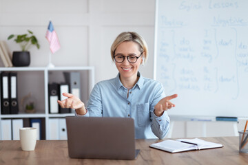 Learning English online. Happy female teacher giving foreign language lesson on internet using...