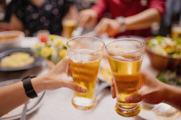 Close-up of people cheering of beer at a party. Group of Asian people having a New Year's party at home.