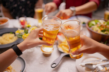 group of Asian people clink glasses and drink beer at the party. They are very happy.