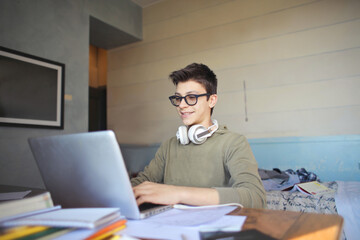 young boy uses his laptop in his bedroom