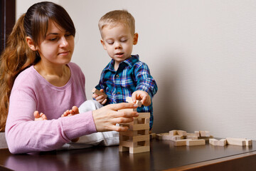 baby with mom playing in wooden blocks