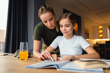 Beautiful focused military woman doing homework with her daughter at home