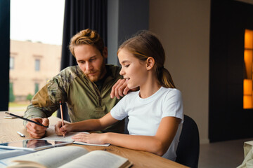 Masculine focused military man doing homework with her daughter at home