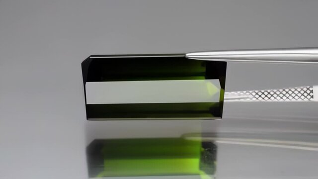 Natural green tourmaline on the  grey background