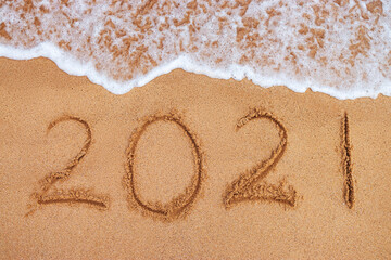 Happy New Year 2021 concept, lettering on the beach. Written text on the sea beach at sunrise.