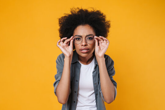 Confused african american girl in eyeglasses looking at camera