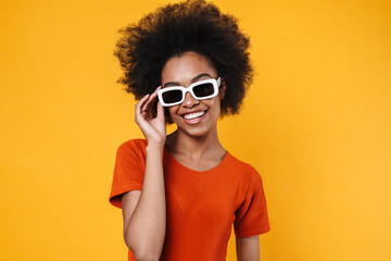 Joyful african american girl in sunglasses smiling and looking at camera