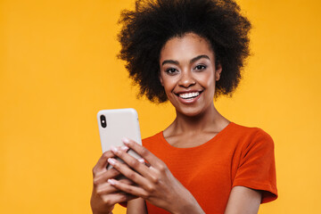 Joyful african american girl smiling while using mobile phone