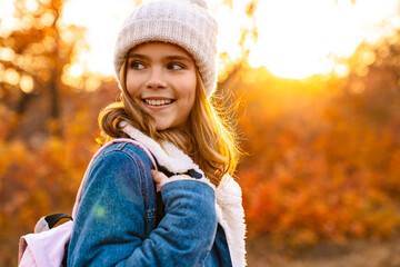 Smiling girl in knitted hat walking in the autumn park