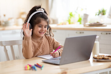 Distance Learning. Cute little home schooler girl having video lesson with laptop