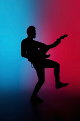 Party. Silhouette of young male guitarist isolated on blue-pink gradient studio background in neon. Beautiful shadow in action, performing. Concept of human emotions, expression, ad, music, art.