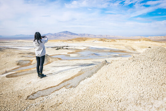Female tourist person takes a photo of stunning landscape of mud volcanoe in Chachuna managed reserve