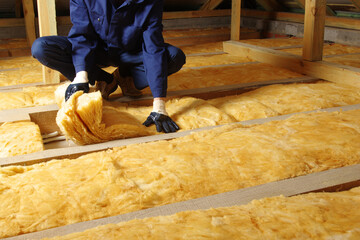 Man installing thermal insulation layer under the roof - 401005223