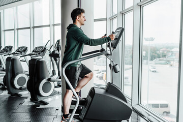 A handsome young man is training on a stepper. Stylish, modern gym. Healthy Lifestyle