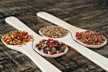 A mixture of various spices in a wooden spoon. Spices and seasonings on an old shabby board. Mix on a pile close up.