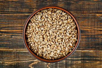 Sunflower seeds in a clay bowl on an old shabby board. Nuts on a brown wooden table.