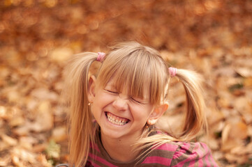 Fototapeta premium Happy child. The girl laughs. Blonde girl in the autumn park.