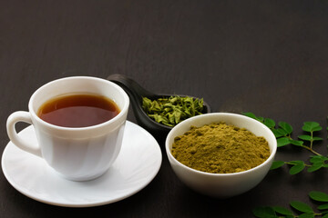 moringa tea in white cup ceramic and moringa leaf on black wooden background