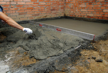 worker screeding indoor cement floor with screed