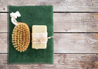 Natural soap and massage brush with a towel on a wooden background with space for text. The concept of cleanliness and ecology.