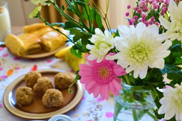 Closeup of a brunch table with sweet and savory food and a vase with flowers