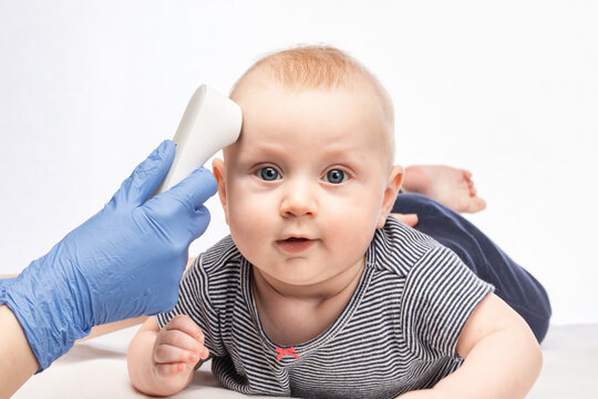 Doctor Checking Body Temperature Of Baby Boy With Infrared Thermometer