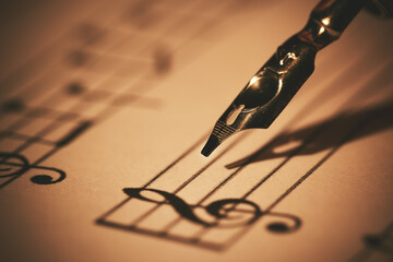 writing musical notes on sheet with quill pen and ink. music education. closeup - obrazy, fototapety, plakaty