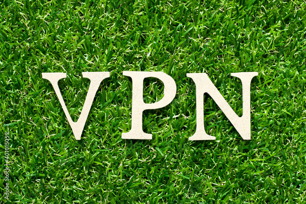 Wall mural Wood alphabet letter in word VPN (abbreviation of virtual private network) on green grass background