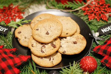 Chocolate chip cookies with Christmas theme on black plate.