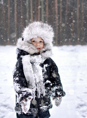 The boy in his winter clothes was cold. Snow is falling