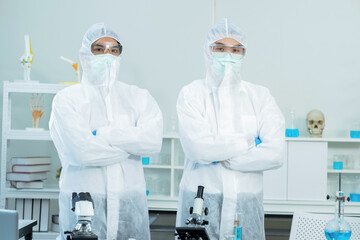 Two scientists wearing personal protective and safety glass standing and crossed arms in the laboratory. Research on the coronavirus vaccine to prevent COVID-19. Medical and health concept.