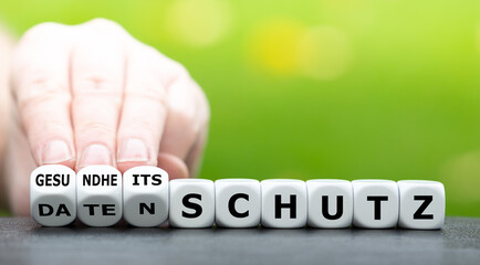 Datenschutz oder Gesundheitsschutz? Hand dreht Würfel und ändert das Wort Datenschutz in...