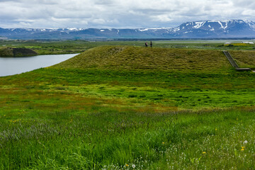 Fototapeta na wymiar Unrecognisable people on the coastline around the pond Stakholstjorn with pseudo craters - natural monument near Lake Myvatn in Northern Iceland in summer