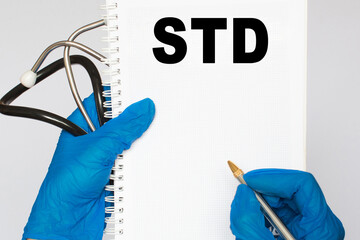 The doctor's blue - gloved hands show the word STD - . a gloved hand on a white background. Medical concept. the medicine