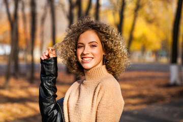 Hairstyle curly hair, portrait of a young blonde girl in an autumn park