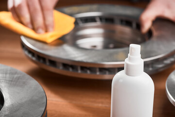 Close-up on an anti-rust spray and man cleaning a brake rotor in the background