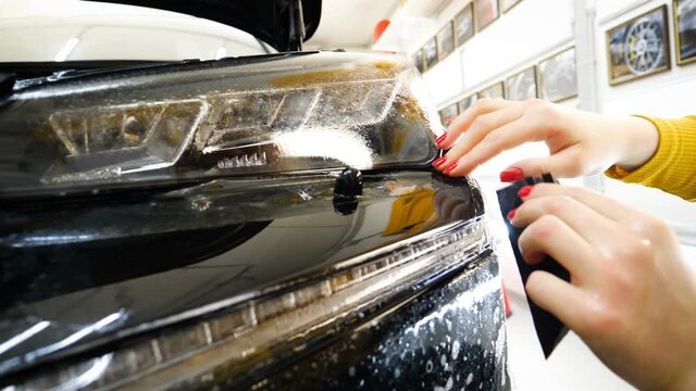 Close up to PPF installation process on a front rear headlight and bamper. PPF is a Paint Protection Film which protect paint