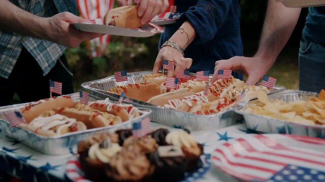 People taking hotdogs at a 4th of July picnic 