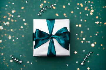 Gift box with bow on green, sea color background with sparkles.