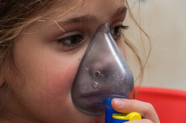 Little girl child makes inhalation with mask on face