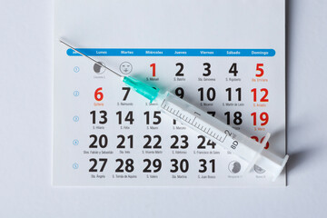 Coronavirus vaccine calendar with syringe on white background