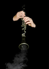 The player on the smoking clarinet on black background