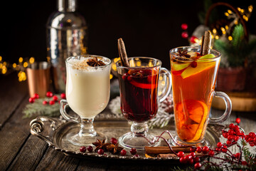 fresh yellow eggnog, grog and fruity red mulled wine with Christmas decoration. Selection of autumn or winter alcoholic hot drinks