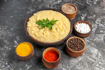 bottom view mashed potatoes in wooden bowl sea salt black pepper red pepper turmeric in small bowls on dark background