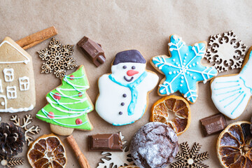 Gingerbread painted colored gingerbread cookies and spices and snowflakes on a craft background close-up. Christmas celebration concept. New Year's food. Copy space