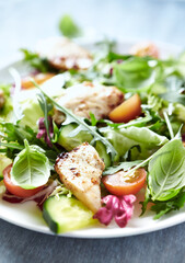 Salad with Chicken Breast, Cherry Tomatoes, Cucumber, Rocket and fresh Basil. Bright wooden background. Close up. 