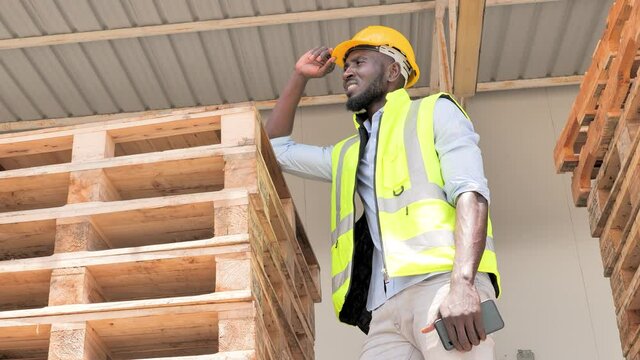 Portrait logistic concept, a man worker is thinking and stand on pallet and gesture say hi for something else to a coworker with warehouse background, worker business concept, and copy space.
