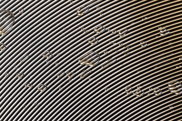 bstract background of water drops on an aluminum surface with radial paths, thin parallel lines on metal and water drops