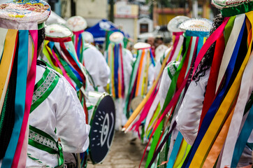 Fitas coloridas e pessoas tocando tambores na Congada, manifestação cultural e religiosa afro-brasileira