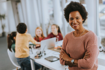African American female science teacher with group of kids programming electric toys and robots at robotics classroom